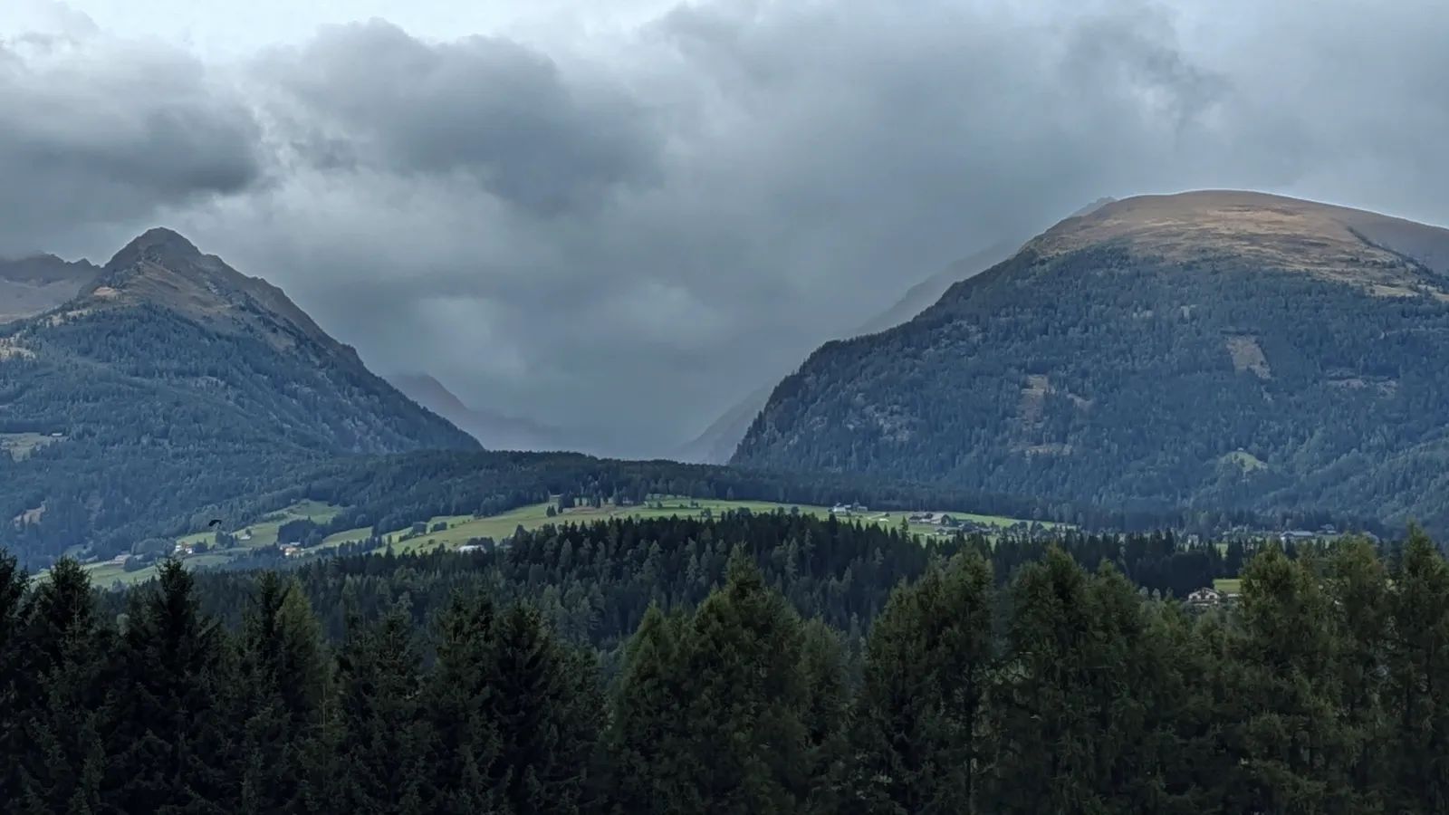 Stormy alpine valley with dark clouds and mountain walls