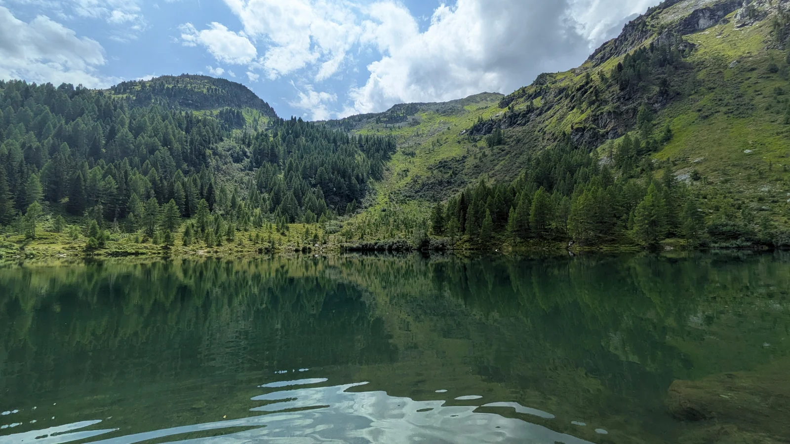 Wirpitschsee reflecting forested alpine slopes in the Weißpriachtal, Lungau.