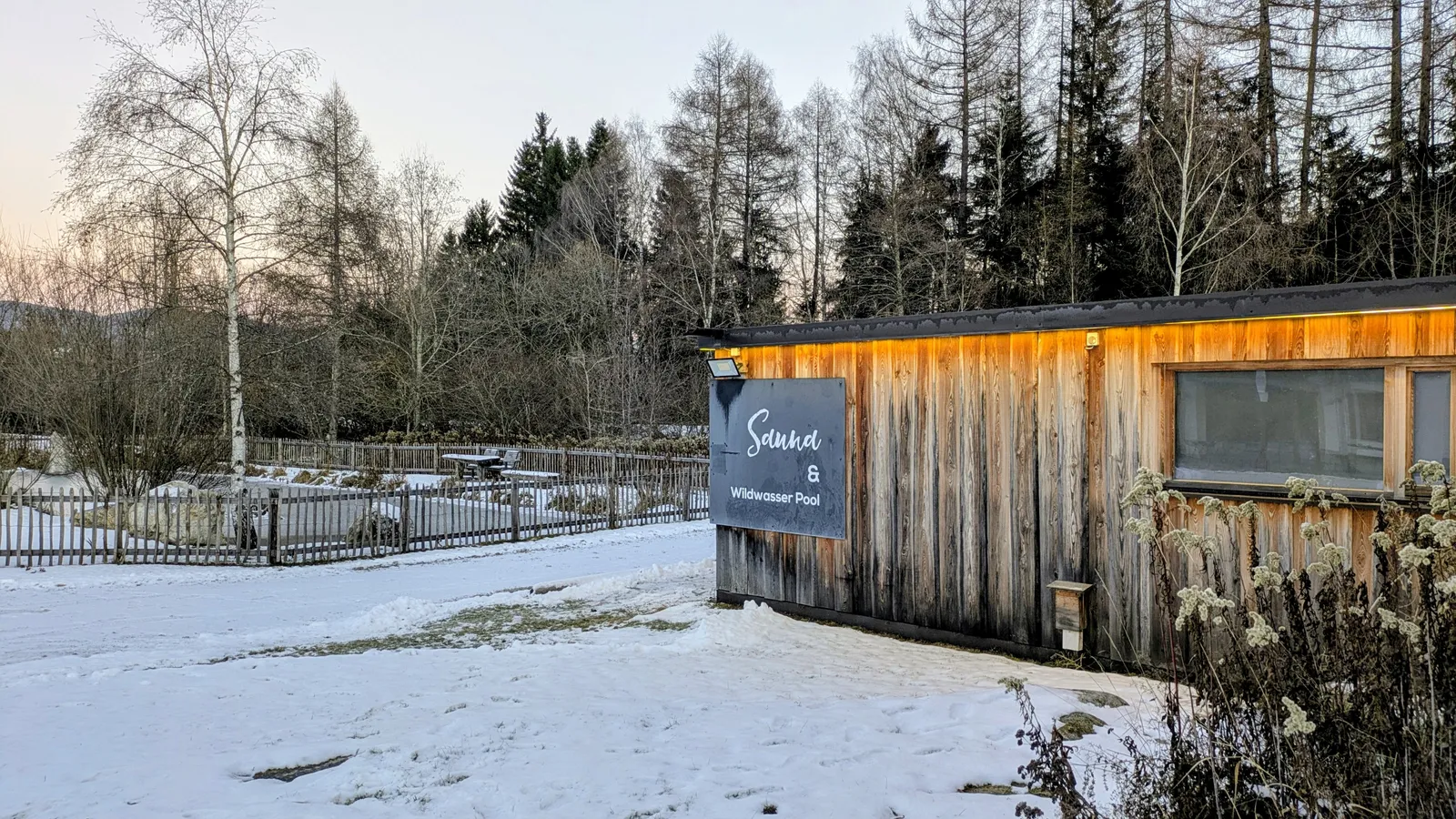 Small wooden sauna or wellness building in a snowy setting