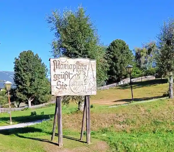 Traditional welcome sign reading Mariapfarr grüßt Sie in a village park.